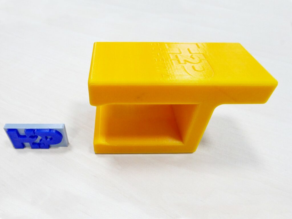 3D tištěná zarážka z PLA (vpravo) zabraňuje pádu dílů na válečkové trati